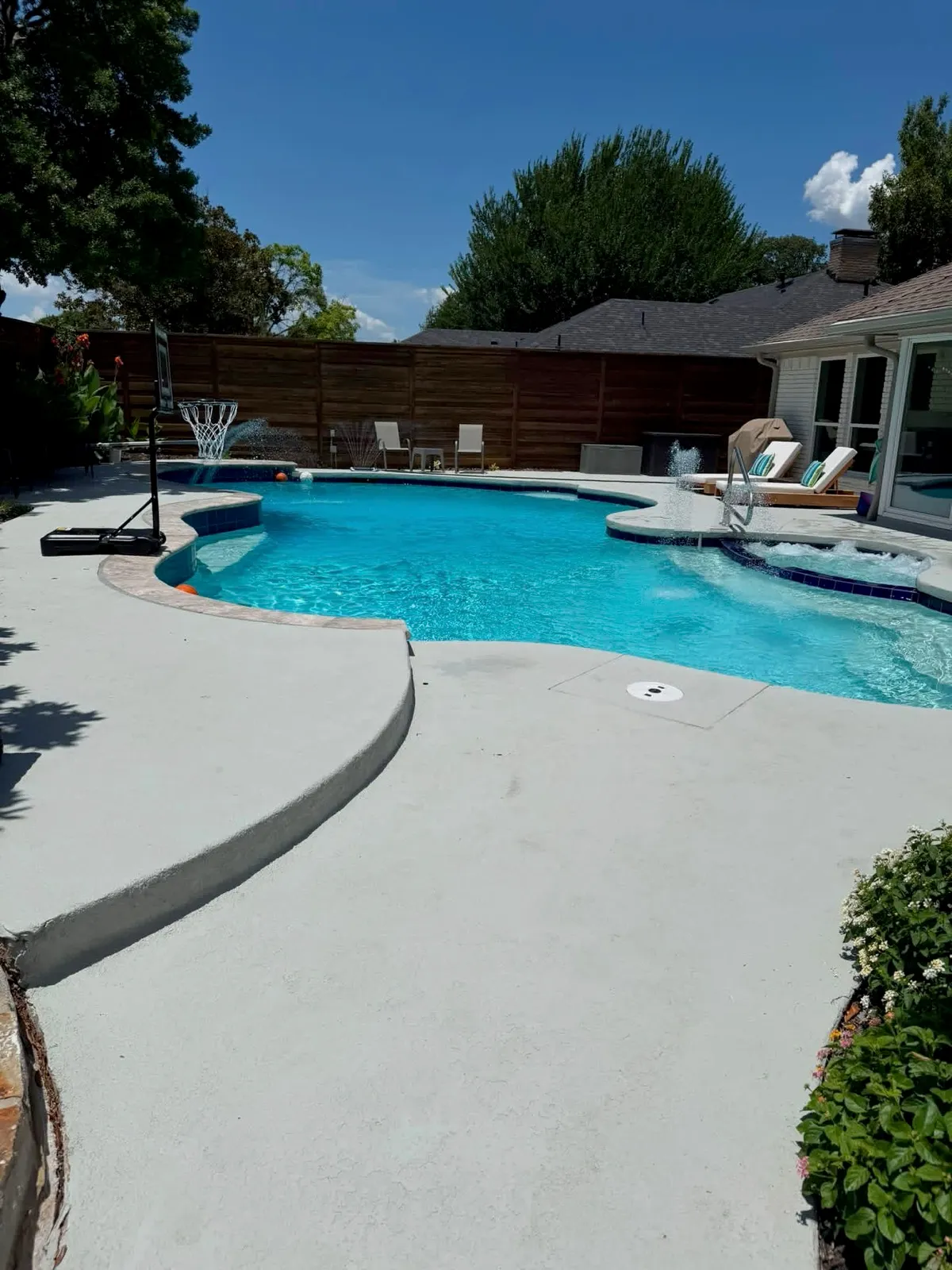 A residential pool and spa in a Dallas back garden, water clear and the spa spillover running